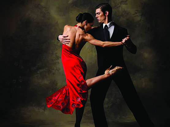 Una coppia balla appassionatamente il tango argentino, la donna viene mantenuta dall'uomo in una posizione a caschè, la donna ha un